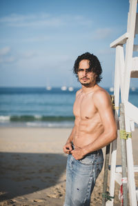 Young man standing at beach against sky