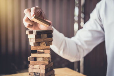 Midsection of man stacking wooden blocks on table