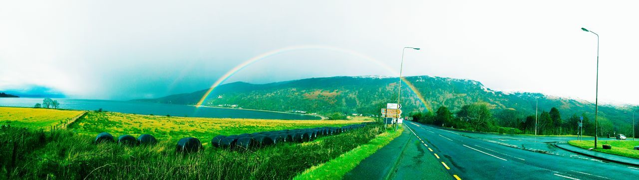 mountain, transportation, road, landscape, the way forward, sky, scenics, tranquil scene, tranquility, nature, country road, beauty in nature, grass, mountain range, diminishing perspective, rainbow, green color, panoramic, field, copy space