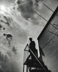 Low angle view of silhouette man standing on staircase against sky