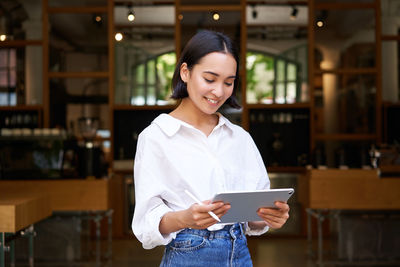 Portrait of young woman standing in library