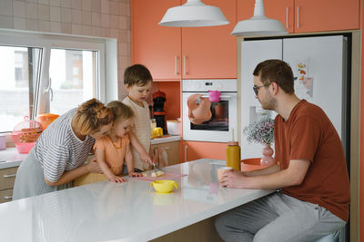 Happy family with kids cooking on modern kitchen. children cutting fruit salad, preparing food with