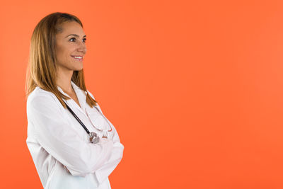 Portrait of young woman standing against yellow background