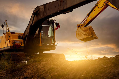 Backhoe at construction site digging soil with bucket of backhoe. bulldozer on sunset sky. digger 