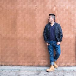Full length of man standing against brick wall