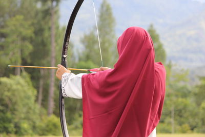 Rear view of muslim woman holding arrow
