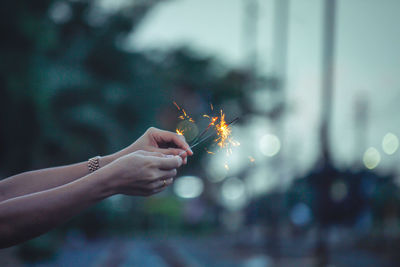 Close-up of hand holding sparkler against blurred background