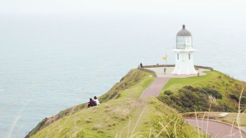 Lighthouse amidst sea and buildings against sky