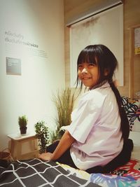 Side view of smiling girl looking away while sitting at home