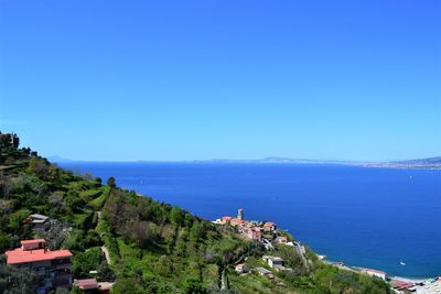 High angle view of townscape by sea against clear blue sky