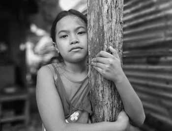 Portrait of cute girl holding wood column 