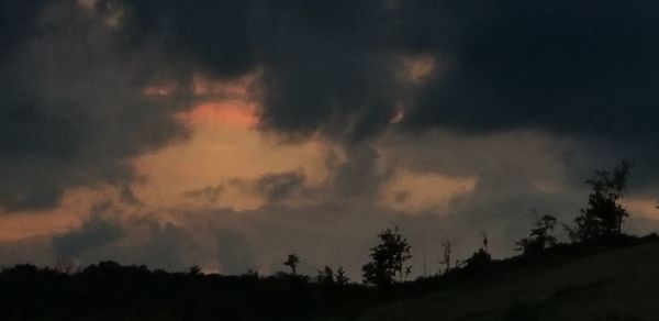 Low angle view of silhouette trees against dramatic sky