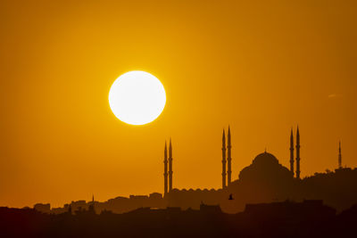 Silhouette of temple against orange sky