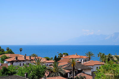 Buildings by sea against blue sky