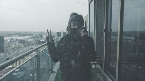 Man photographing cityscape through window