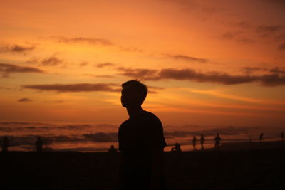 Silhouette man standing on beach against sky during sunset