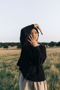 Young woman touching face while standing at park