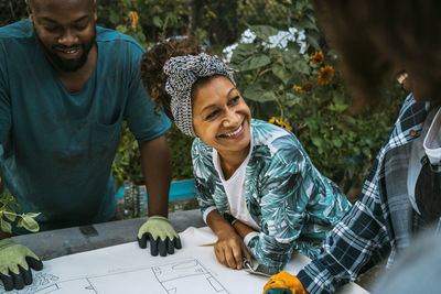 Happy male and female volunteers talking in urban garden