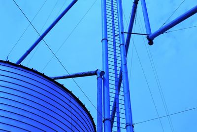 Low angle view of storage container and cables against sky in industry