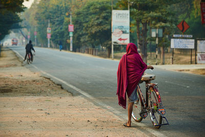 Rear view of people riding bicycle on road