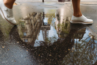 Close up photo of girl stepping over a puddle. in the puddle reflected eiffel tower. 