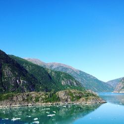 Scenic view of lake and mountains against clear blue sky