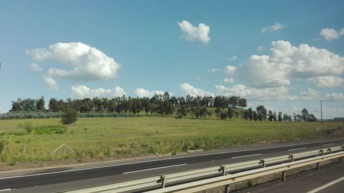 Road by field against sky