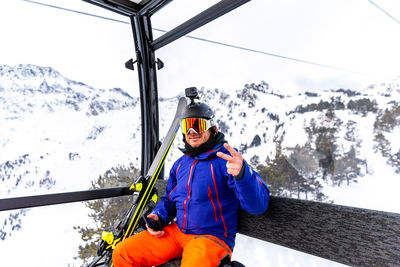 Portrait of man gesturing peace sign while sitting in cable car