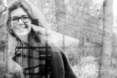 Cheerful woman wearing eyeglasses seen through glass window