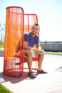 A man sitting outside in a colorful modern chair.