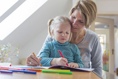 Mother and daughter coloring on book