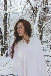 Woman wrapped in white fabric at forest during winter