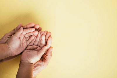 Cropped hand of woman against yellow background