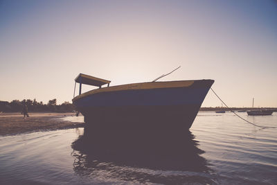 Boat moored on beach against clear sky