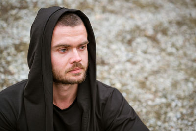 Portrait of young man outdoors with an unshaven face in a dark sweater