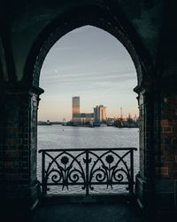 Bridge over river by buildings against sky