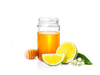 Close-up of honey and lemon against white background