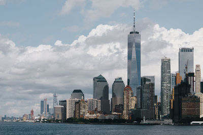 Sea by modern buildings against sky in city