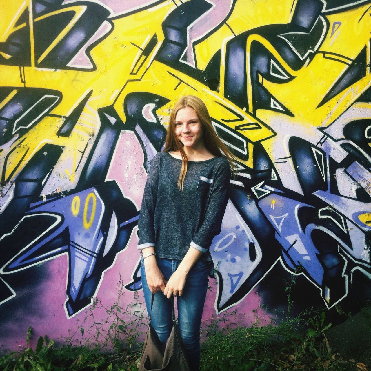 lifestyles, young adult, person, casual clothing, leisure activity, looking at camera, portrait, front view, young women, standing, graffiti, smiling, three quarter length, happiness, wall - building feature, art, architecture