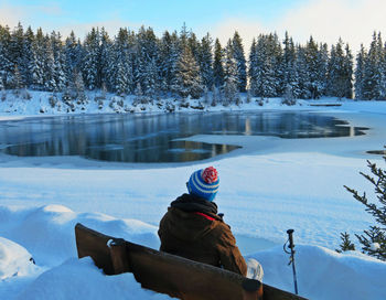 Woman on snow covered trees by lake during winter