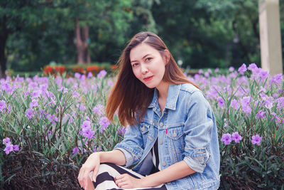 Beautiful young woman sitting on purple flowering plants