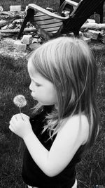 Side view of girl holding plant on field