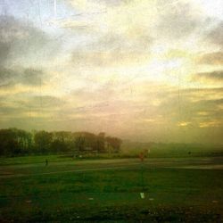 Scenic view of grassy field against cloudy sky