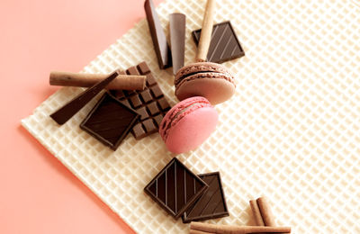 Macarons, chocolates, cinnamon sticks on waffle background. sweet food concept.
