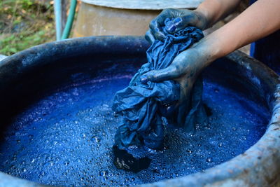 Cropped hands of woman washing textile in blue water