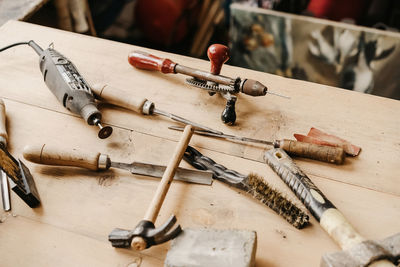 From above of various weathered professional instruments for woodwork arranged on wooden table in carpentry workshop