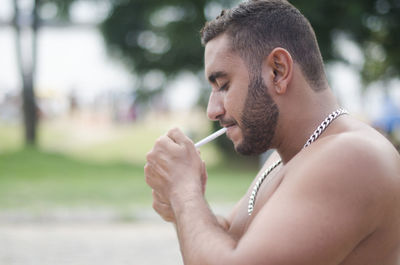 Portrait of man igniting cigarette outdoors