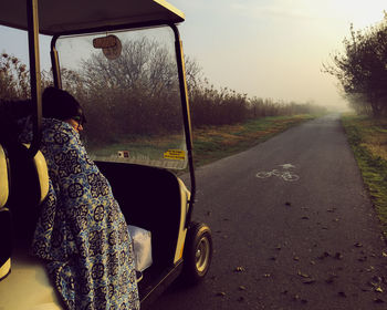 Boy sitting in golf cart on road