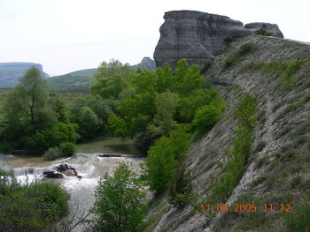 Scenic view of river amidst rocks and trees against sky