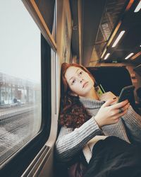 Young woman using mobile phone in train